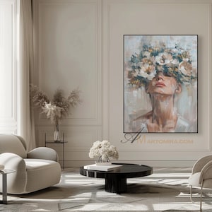 K&ouml;nnte beinhalten: Gerahmtes Gem&auml;lde einer Frau mit geschlossenen Augen und einem Blumenkranz. Das Kunstwerk verwendet eine ged&auml;mpfte Farbpalette aus Beige, Wei&szlig; und Hellblau, wodurch eine ruhige &Auml;sthetik entsteht. Das Kunstwerk wird in einem modernen Wohnzimmer gezeigt.