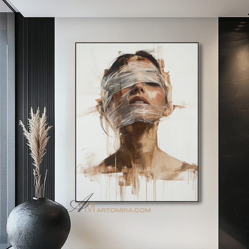 May include: An abstract portrait painting of a person with their eyes covered by a transparent material. The artwork features a neutral color palette with shades of brown and white, and is framed in a black border. The painting is displayed on a white wall.