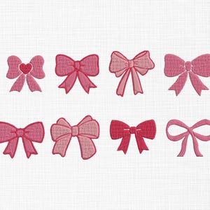 May include: Eight embroidered bows in shades of pink are displayed on a white background. The bows vary in style, with some featuring a heart detail or layered design. The embroidery has a textured appearance.