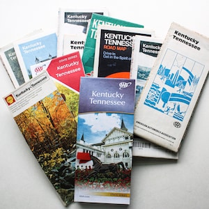 May include: A collection of vintage road maps for Kentucky and Tennessee, featuring the AAA logo and state series branding. The maps are in various colors, including blue, red, and green, and have a worn, vintage look.