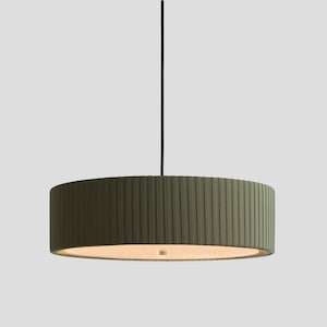May include: A cylindrical pendant light fixture featuring a dark olive green pleated fabric shade. The lamp is suspended by a single thin black cord and includes a circular white diffuser panel at the bottom, emitting a soft, warm light.