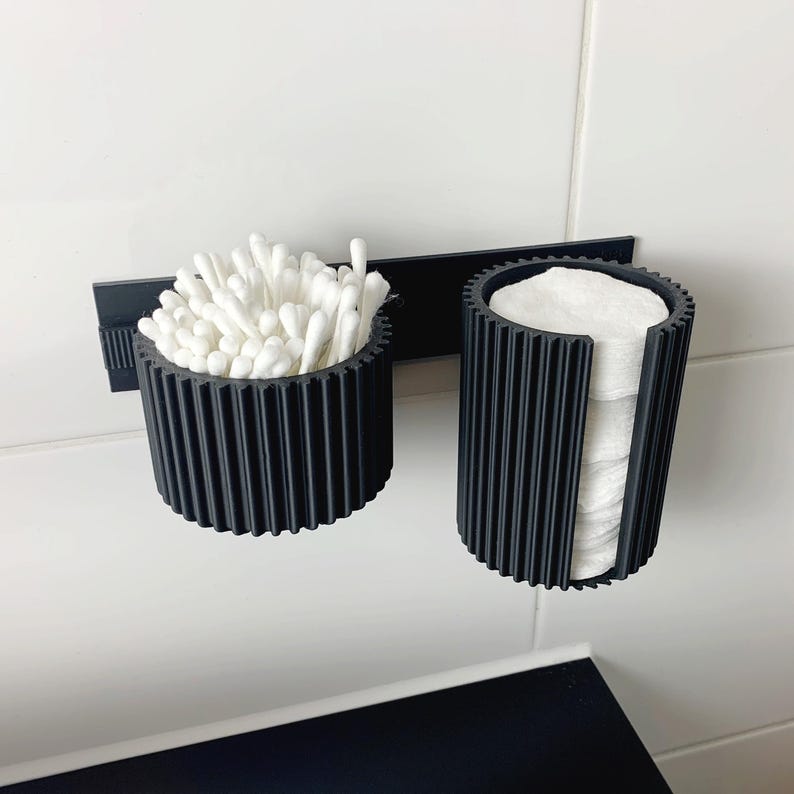 May include: A white ceramic mug with a black handle and the text "But First, Coffee" in a bold, black font. The mug is set against a blurred background, suggesting a cozy setting.