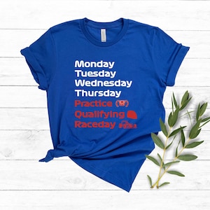 May include: A royal blue t-shirt with white and red text. The text lists the days of the week, followed by "Practice", "Qualifying", and "Raceday". The shirt has a crew neck and short sleeves.