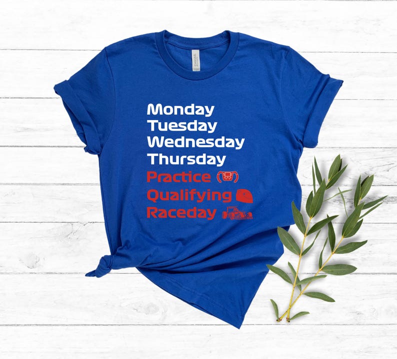 May include: A royal blue t-shirt with white and red text. The text lists the days of the week, followed by "Practice", "Qualifying", and "Raceday". The shirt has a crew neck and short sleeves.