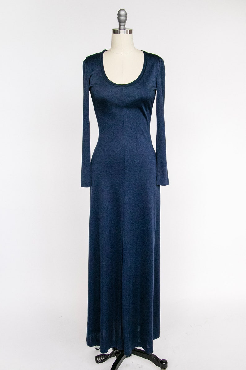 Puede incluir: Un vestido largo de color azul marino con mangas largas y cuello redondo. El vestido est&aacute; ajustado en el corpi&ntilde;o y se ensancha en una falda completa.