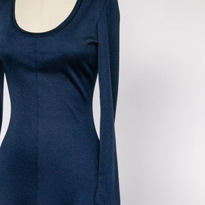Puede incluir: Un vestido largo de manga larga de color azul marino con escote redondo. El vestido est&aacute; ajustado en el cuerpo y se ensancha ligeramente en la falda.