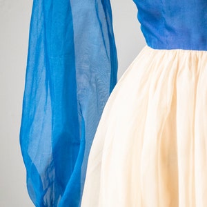 May include: A blue and white dress with long, sheer sleeves. The sleeves have a colorful trim at the wrist.