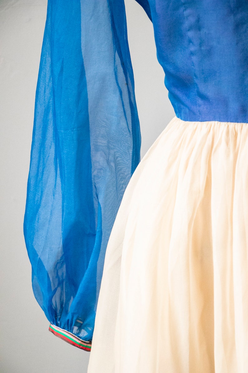 May include: A blue and white dress with long, sheer sleeves. The sleeves have a colorful trim at the wrist.