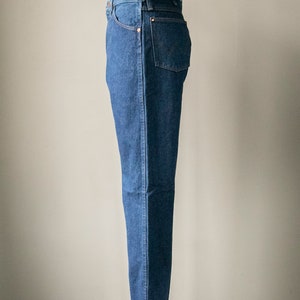 Puede incluir: Un par de pantalones vaqueros azules de mezclilla en un maniqu&iacute;. Los pantalones tienen una pierna recta y un dise&ntilde;o cl&aacute;sico de cinco bolsillos.