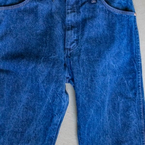 May include: A pair of blue denim jeans with a classic five-pocket style. The jeans have a straight leg and a button fly.