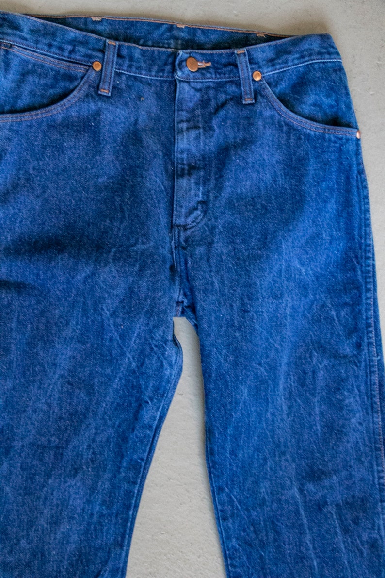 May include: A pair of blue denim jeans with a classic five-pocket style. The jeans have a straight leg and a button fly.