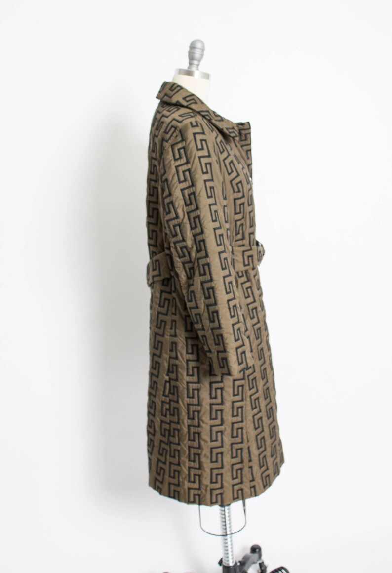 May include: A long, brown coat with a black geometric pattern. The coat has a belt and a collar.