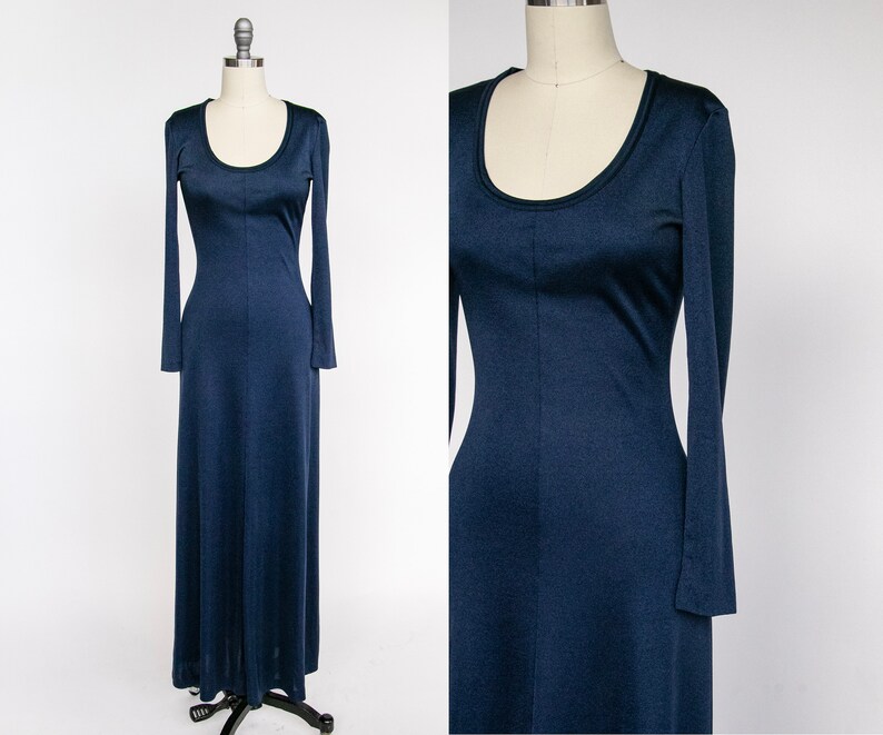 Puede incluir: Un vestido largo de manga larga de color azul oscuro. El vestido tiene un escote redondo y un corpi&ntilde;o ajustado. Las mangas son largas y fluidas.