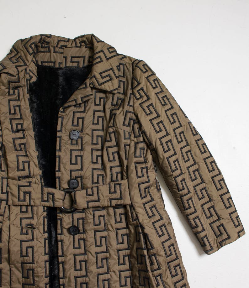 May include: A long brown quilted coat with a black geometric pattern. The coat has a black fur lining, a belt, and two buttons.