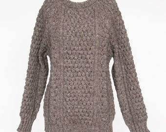 May include: A brown cable knit sweater with a crew neck. The sweater is made of a thick, textured yarn and has a loose fit.