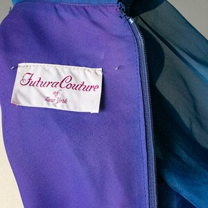 May include: A purple and blue dress with a zipper closure and a white label that reads "Futura Couture of New York".