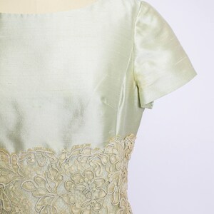 May include: A light green dress with a lace trim around the waist. The dress has short sleeves and a scoop neck.
