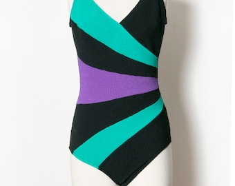 May include: A black swimsuit with teal and purple geometric stripes.