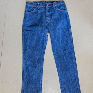 May include: A pair of blue denim jeans with a classic straight leg fit. The jeans have a button fly and five pockets.