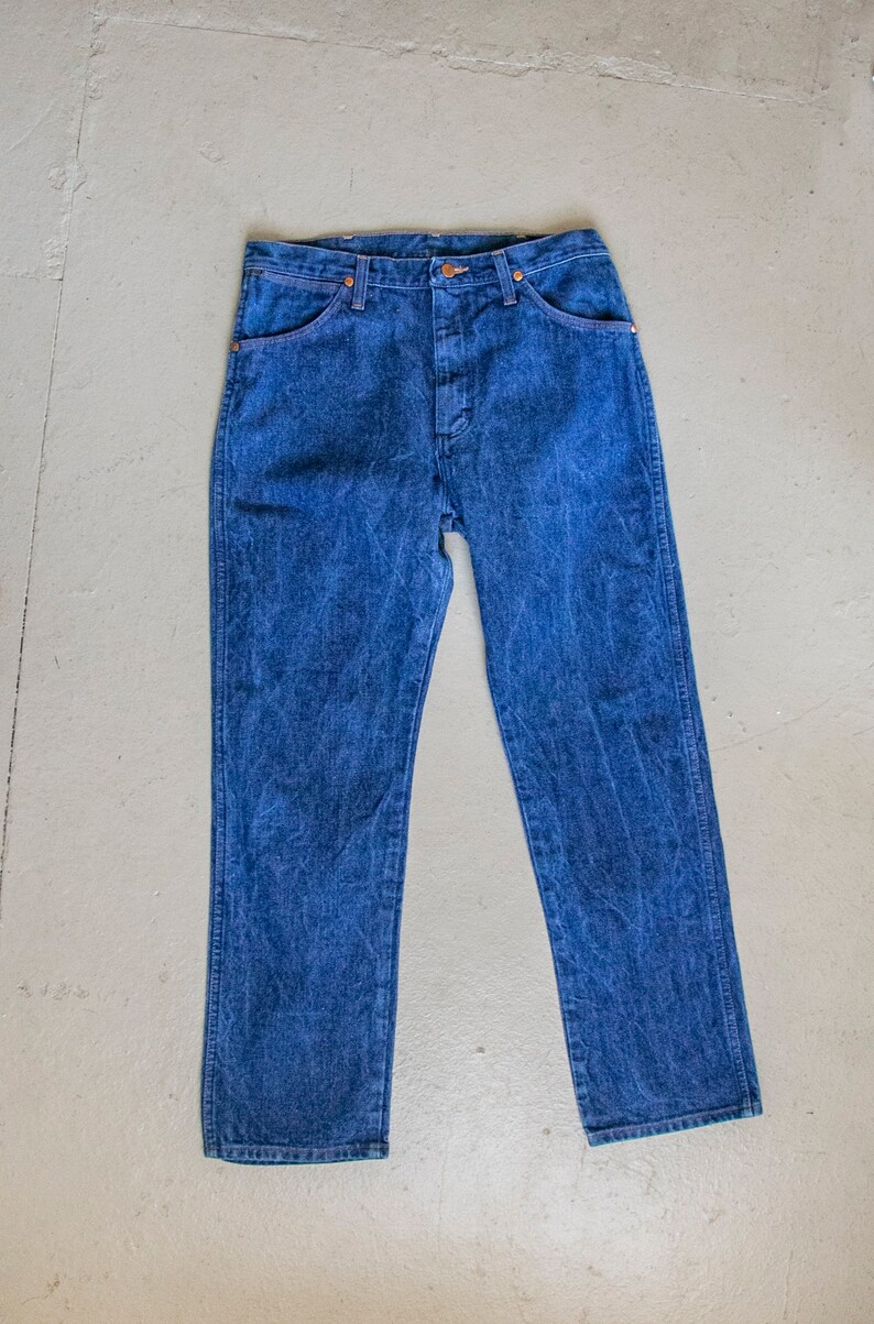 May include: A pair of blue denim jeans with a classic straight leg fit. The jeans have a button fly and five pockets.