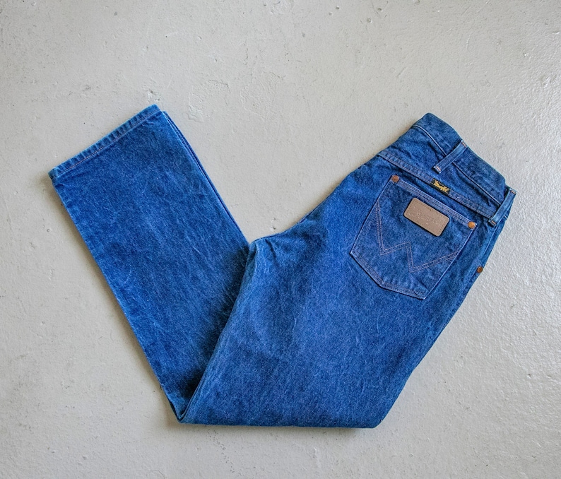 May include: A pair of blue denim jeans with a brown leather patch that says "Wrangler" on the back pocket.
