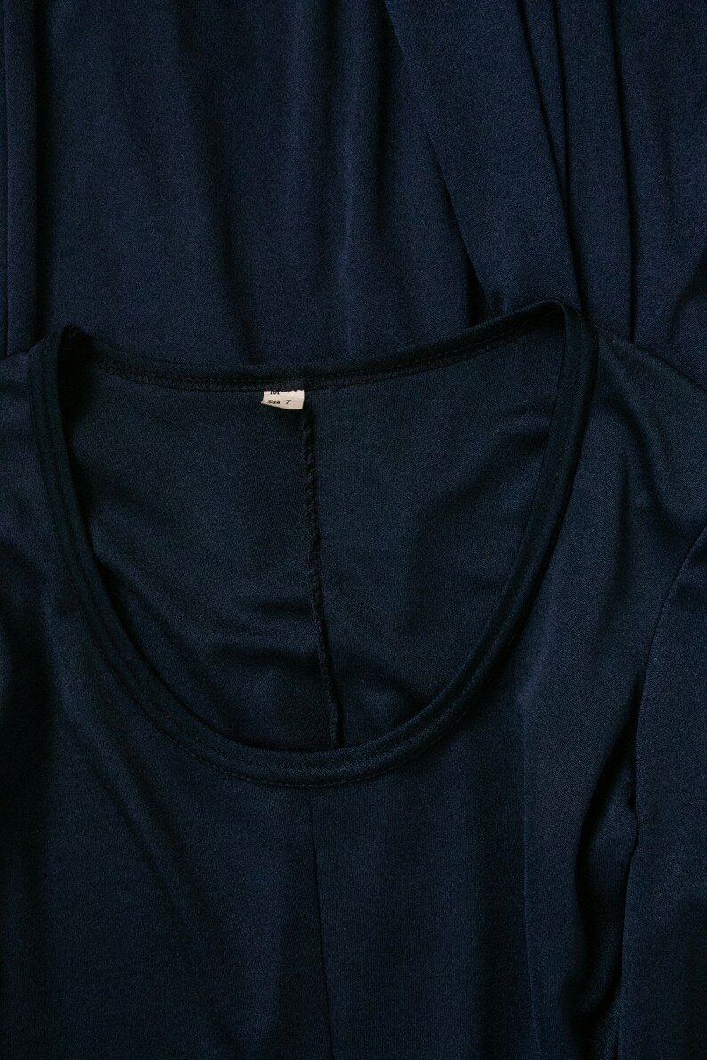 Puede incluir: Una camisa azul marino de manga larga con cuello redondo. La camisa tiene una peque&ntilde;a etiqueta blanca con el texto "M" y "Hecho en China" en ella.