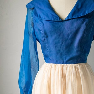 May include: A vintage dress with a blue bodice and a white tulle skirt. The bodice has a wide, sailor-style collar and long sleeves.