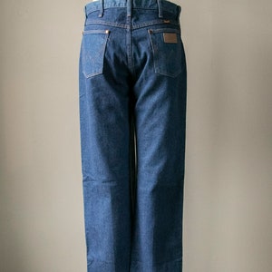 Puede incluir: Un par de pantalones vaqueros azules de mezclilla con un parche de cuero marr&oacute;n en el bolsillo trasero. Los pantalones est&aacute;n en un maniqu&iacute;.