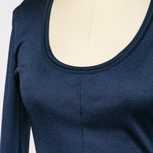 Puede incluir: Una camisa azul marino de manga larga con cuello redondo.