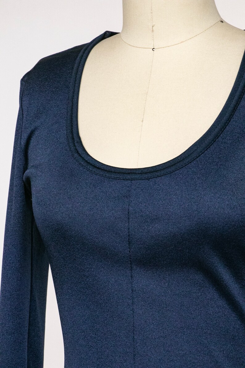 Puede incluir: Una camisa azul marino de manga larga con cuello redondo.