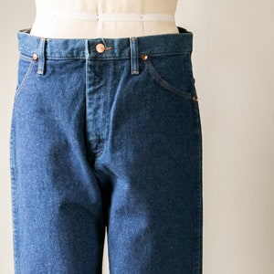 Puede incluir: Un par de pantalones vaqueros de color azul oscuro con un corte cl&aacute;sico de pierna recta. Los vaqueros tienen cierre de bot&oacute;n y trabillas para el cintur&oacute;n.
