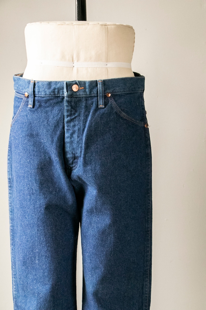 Puede incluir: Un par de pantalones vaqueros de color azul oscuro con un corte cl&aacute;sico de pierna recta. Los vaqueros tienen cierre de bot&oacute;n y trabillas para el cintur&oacute;n.