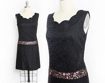 May include: A black lace dress with a scalloped neckline and a sheer lace band at the waist.