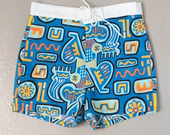 May include: Blue and orange patterned swim trunks with a white waistband and drawstring. The pattern features geometric shapes and abstract designs.