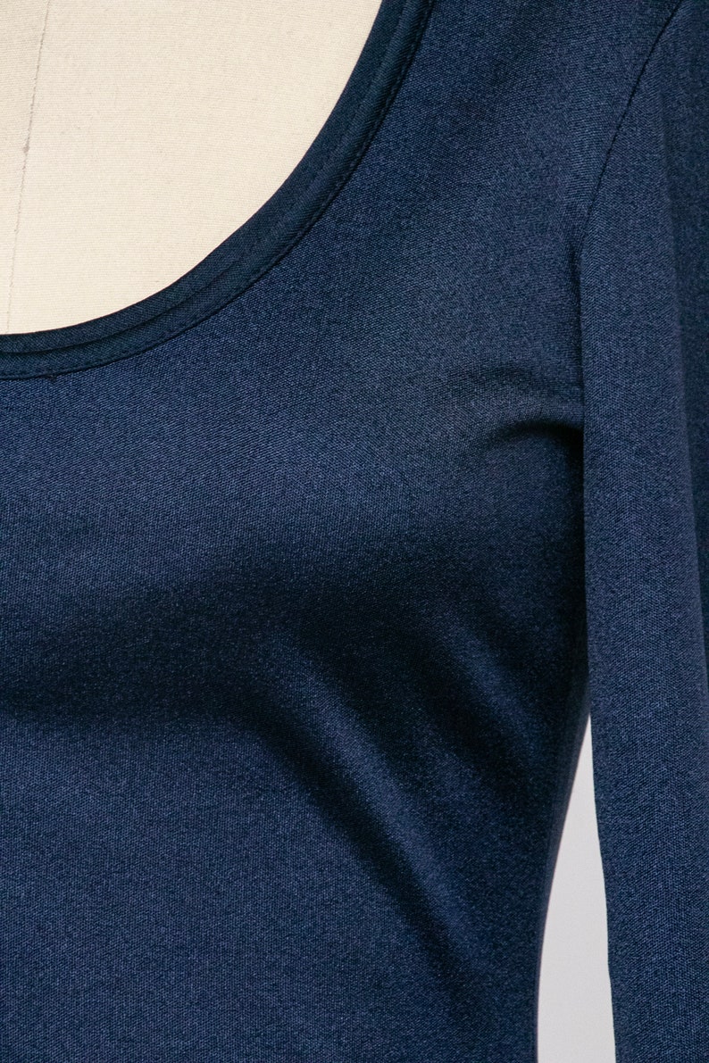 Puede incluir: Una camisa de manga larga azul marino con cuello redondo.