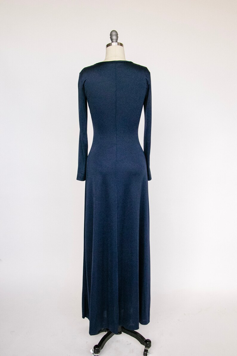 Puede incluir: Un vestido largo de maxi azul marino con mangas largas y un corpi&ntilde;o ajustado. El vestido est&aacute; hecho de una tela suave y el&aacute;stica y tiene un dise&ntilde;o simple y elegante.