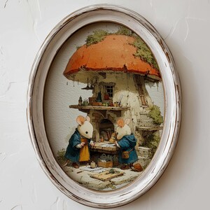 May include: An oval framed print depicting two mice in blue coats working at a table in front of a mushroom-shaped house. The frame is white with a distressed finish. The mushroom has a red cap and the artwork has a whimsical style.