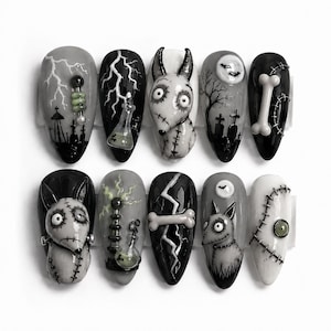 May include: A set of ten press-on nails featuring a gothic theme with black, white, and gray color palettes. Designs include lightning bolts, tombstones, a full moon with bats, bones, stitched creature motifs, laboratory equipment, and small green accents.