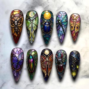 May include: A set of ten almond-shaped nail art tips featuring intricate stained glass designs. Each tip displays a unique insect motif, including moths, beetles, a dragonfly, and a butterfly, rendered in vibrant colours with dark leaded lines.