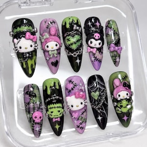 May include: A set of ten almond-shaped press-on nails featuring a Halloween theme with black, purple, and lime green colours. The designs include 3D character figures like Hello Kitty and My Melody, spider webs, stitches, chains, and skulls.