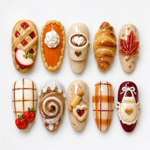 May include: A set of ten decorative nail art pieces featuring miniature food and kitchen themes, including an apple pie, pumpkin pie, coffee mug, croissant, maple leaf, plaid pattern with apples, cinnamon roll, rolling pin, plaid, and an apron.