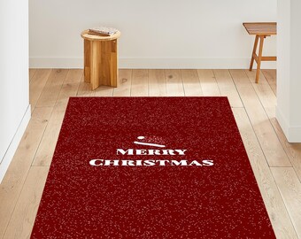 Puede incluir: Una alfombra rectangular roja con un patrón moteado blanco y las palabras "MERRY CHRISTMAS" en blanco. Un gráfico de gorro de Papá Noel blanco está encima del texto. La alfombra está sobre un piso de madera.