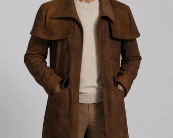 May include: A long brown suede coat featuring a wide collar, a cape-style overlay across the shoulders, and two deep front pockets. The coat is worn over a beige crew-neck jumper and tan trousers, creating a layered look with a textured finish.