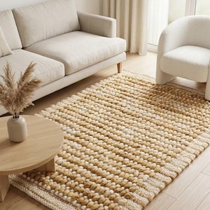 May include: A rectangular area rug featuring a textured surface composed of numerous small, rounded pom-pom-like tufts in alternating shades of cream, beige, and golden brown, arranged in horizontal rows with a flat-woven border at each end.