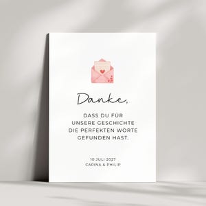 Peut inclure: Une carte rectangulaire blanche avec une illustration à l'aquarelle d'une enveloppe rose ornée d'un petit cœur rouge. Le texte indique : Danke, DASS DU FÜR UNSERE GESCHICHTE DIE PERFEKTEN WORTE GEFUNDEN HAST. 10 JULI 2027 CARINA & PHILIP en noir.