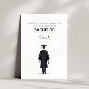 Könnte beinhalten: Eine weiße, rechteckige Glückwunschkarte zum Studienabschluss mit dem Text HERZLICHEN GLÜCKWUNSCH ZUM BESTANDENEN BACHELOR und dem Namen Paul in Schreibschrift. Darunter ist ein Absolvent in schwarzem Talar und Doktorhut mit Diplom abgebildet.