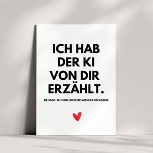 Könnte beinhalten: Ein weißes Poster mit schwarzem Text, der lautet: "ICH HAB DER KI VON DIR ERZÄHLT. SIE SAGT, ICH SOLL DICH NIE WIEDER LOSLASSEN." Unten befindet sich ein kleines rotes Herz. Das Poster lehnt an einer weißen Wand.