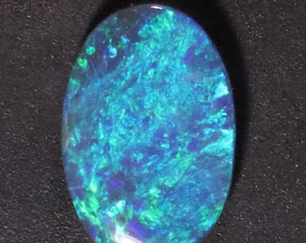 May include: An oval-shaped gemstone with a vibrant display of color. The opal features a mix of blues and greens, creating a dynamic and iridescent effect. The stone is set against a dark background, highlighting its internal play of color.