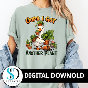 Peut inclure: T-shirt vert clair avec l'inscription "Oops I Got Another Plant" et une oie de dessin animé portant des plantes en pot. L'oie est blanche avec des pieds orange et un sac marron. Le texte est orange et noir.