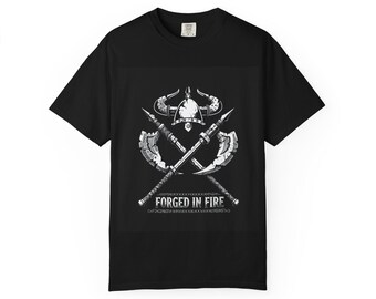 May include: A black short-sleeve t-shirt featuring a white graphic print of a horned helmet positioned above two crossed battle axes. Below the weapons, the text FORGED IN FIRE is printed in a distressed, stylized font with decorative borders.